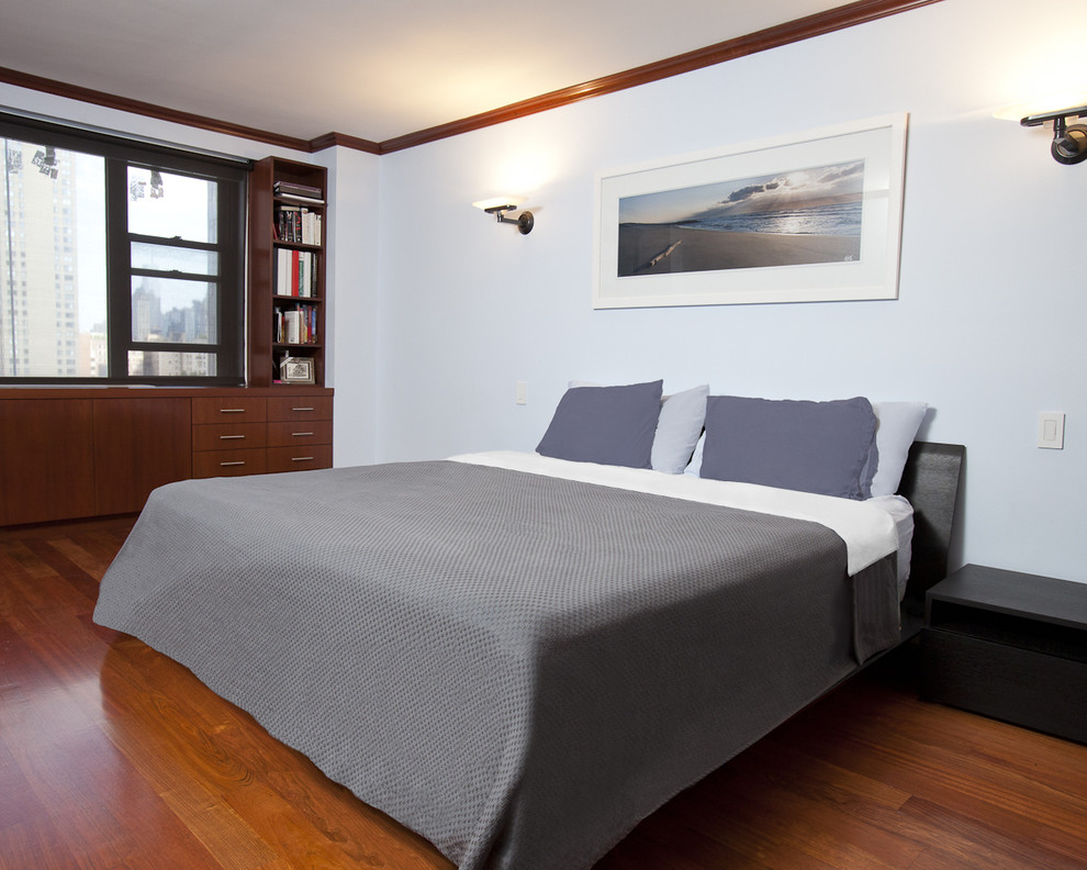 Contemporary bedroom in New York with white walls, medium hardwood floors and no fireplace.