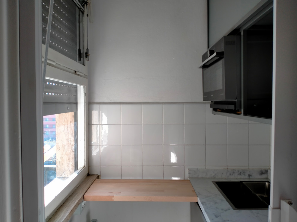 Modern inredning av ett litet vit linjärt vitt kök med öppen planlösning, med en nedsänkt diskho, luckor med lamellpanel, grå skåp, marmorbänkskiva, vitt stänkskydd, stänkskydd i keramik, rostfria vitvaror, terrazzogolv och flerfärgat golv