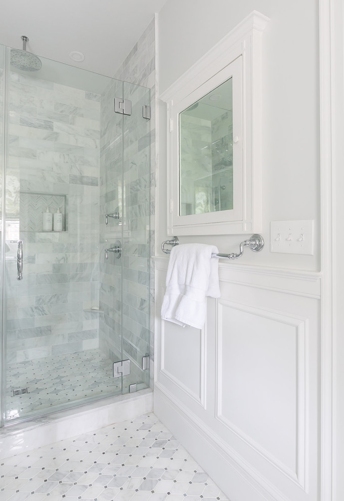 This is an example of a classic bathroom in Baltimore with white cabinets, a walk-in shower, a two-piece toilet, white tiles, marble tiles, white walls, marble flooring, a pedestal sink, marble worktops, white floors, a hinged door, white worktops, a wall niche, double sinks and wainscoting.