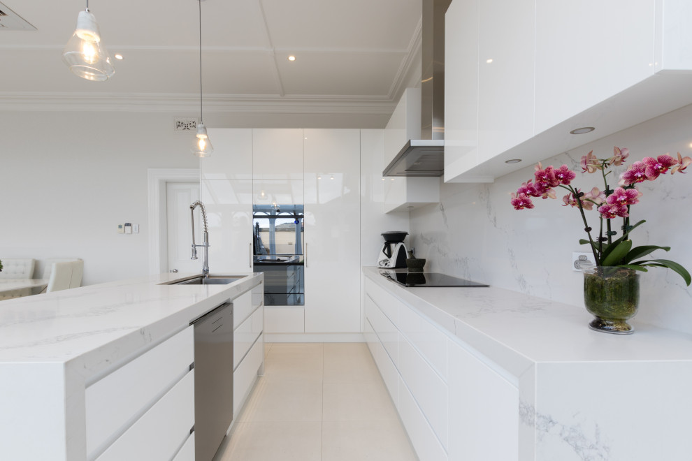 Design ideas for a large contemporary l-shaped kitchen pantry in Melbourne with an undermount sink, flat-panel cabinets, white cabinets, quartz benchtops, engineered quartz splashback, stainless steel appliances, porcelain floors, with island and white benchtop.