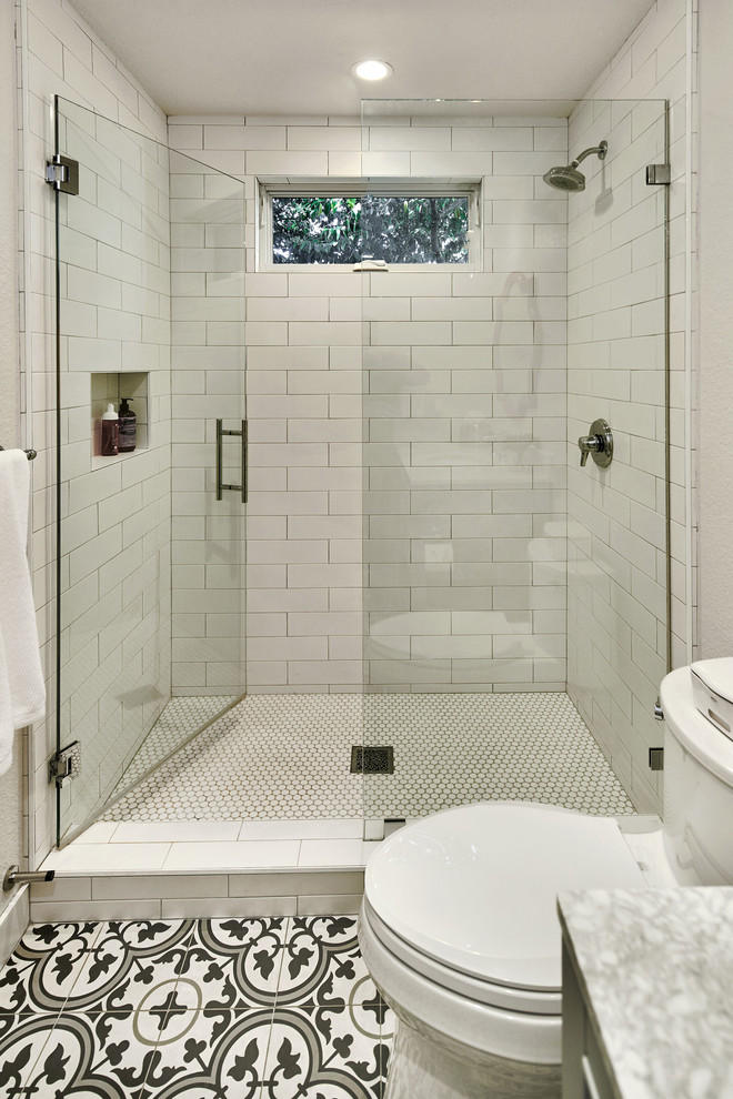 Photo of a mid-sized transitional 3/4 bathroom in San Francisco with furniture-like cabinets, grey cabinets, an alcove shower, a one-piece toilet, white tile, subway tile, white walls, cement tiles, an undermount sink, quartzite benchtops, multi-coloured floor, a hinged shower door and white benchtops.