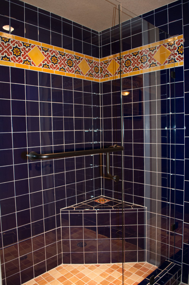 This is an example of a mid-sized transitional master bathroom in Denver with recessed-panel cabinets, medium wood cabinets, an alcove shower, a two-piece toilet, blue tile, ceramic tile, beige walls, terra-cotta floors, a drop-in sink, tile benchtops, red floor and a hinged shower door.
