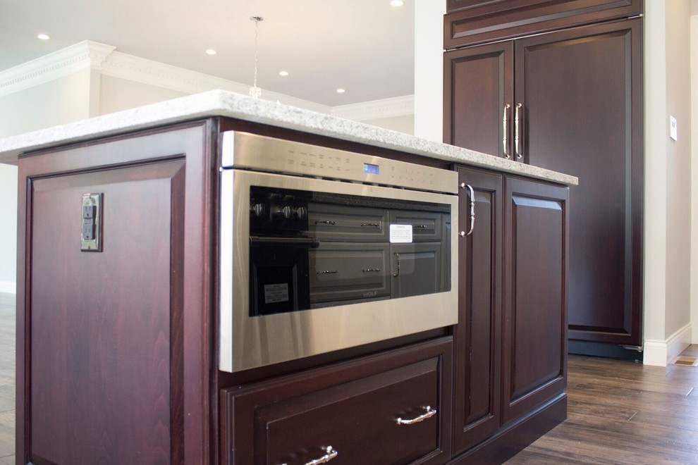 Inspiration for a mid-sized transitional u-shaped dark wood floor and brown floor open concept kitchen remodel in St Louis with an undermount sink, raised-panel cabinets, white cabinets, granite countertops, gray backsplash, stone slab backsplash, stainless steel appliances and an island