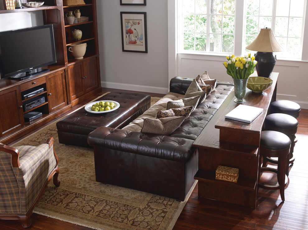 Inspiration for a mid-sized timeless open concept medium tone wood floor and brown floor living room remodel with gray walls, no fireplace and a media wall