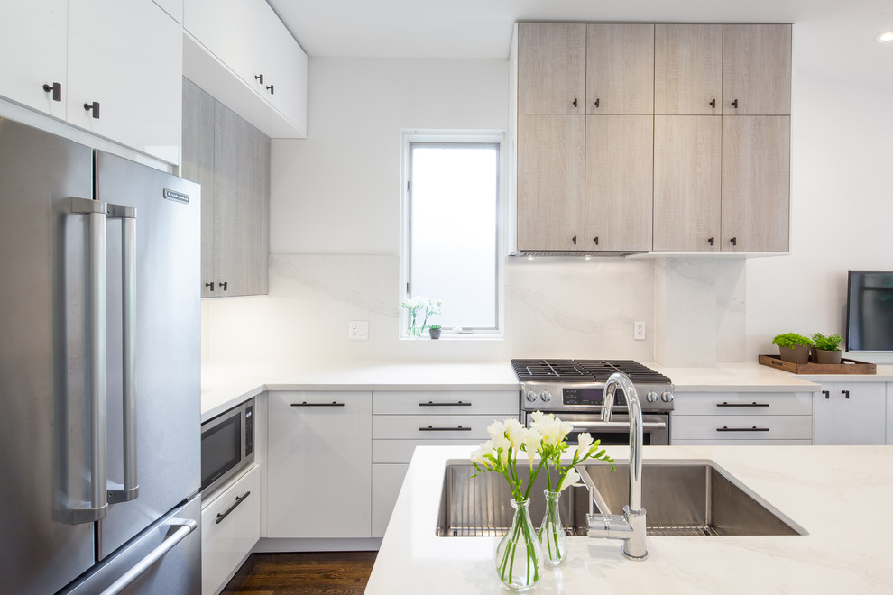 Inspiration for a mid-sized modern l-shaped eat-in kitchen in Toronto with an undermount sink, flat-panel cabinets, white cabinets, marble benchtops, white splashback, stone slab splashback, stainless steel appliances, medium hardwood floors, with island and brown floor.