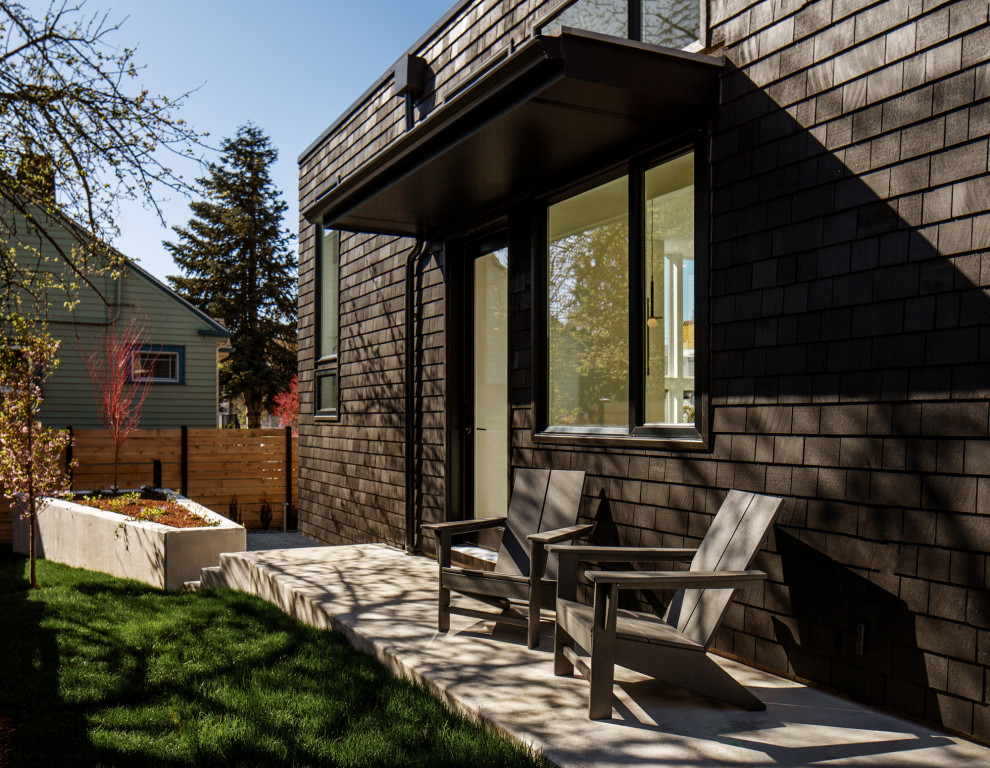 Kleines, Einstöckiges Haus mit schwarzer Fassadenfarbe, Flachdach, grauem Dach und Schindeln in Seattle