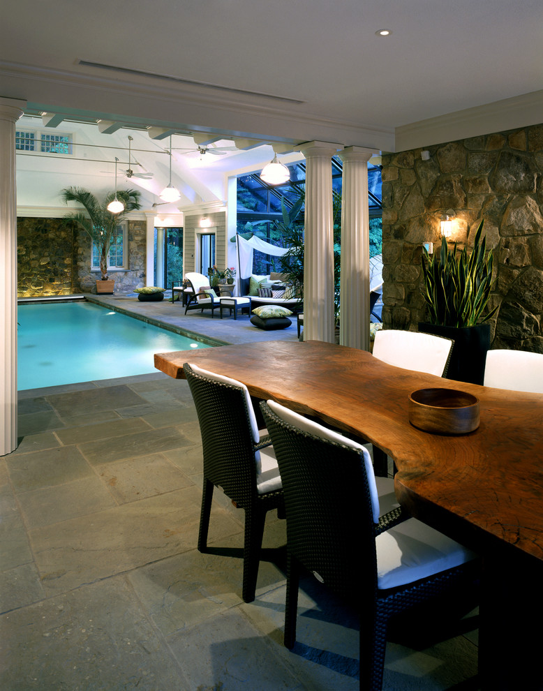 Expansive traditional indoor rectangular pool in New York with a pool house and natural stone pavers.