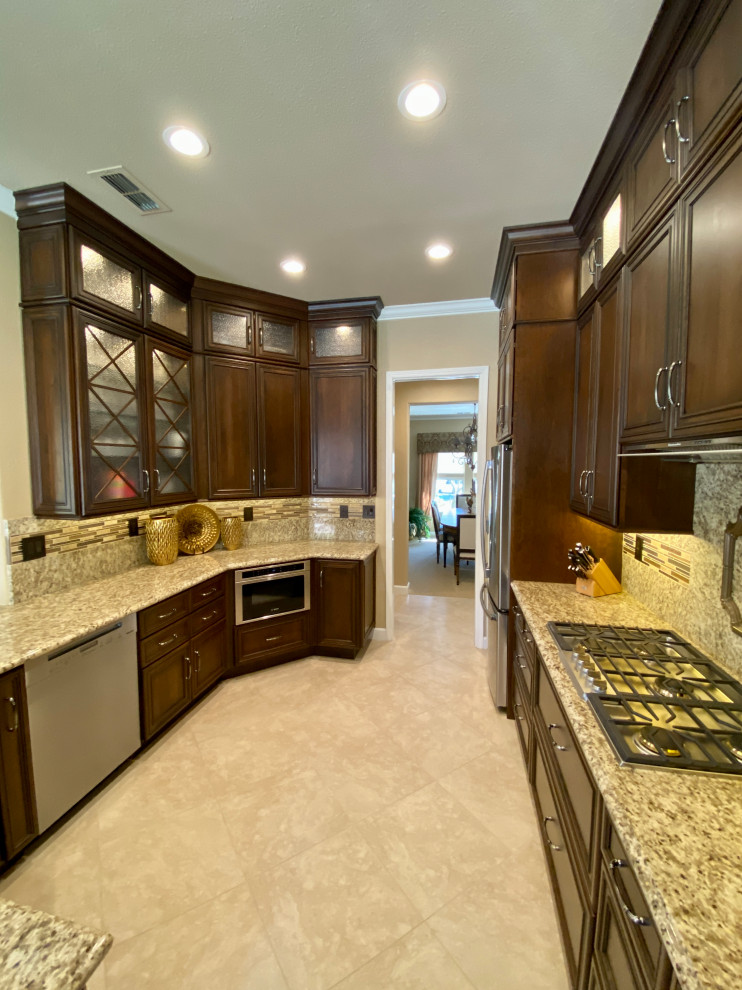 Photo of a large traditional u-shaped open plan kitchen in San Francisco with an undermount sink, raised-panel cabinets, medium wood cabinets, granite benchtops, yellow splashback, granite splashback, stainless steel appliances, porcelain floors, a peninsula, beige floor and yellow benchtop.
