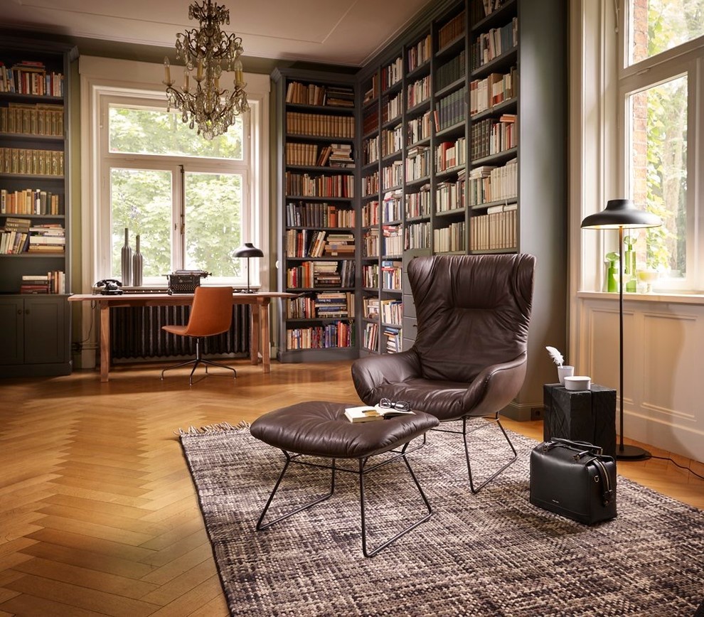 Photo of a large transitional home office in Paris with a library, light hardwood floors, a freestanding desk, green walls and no fireplace.