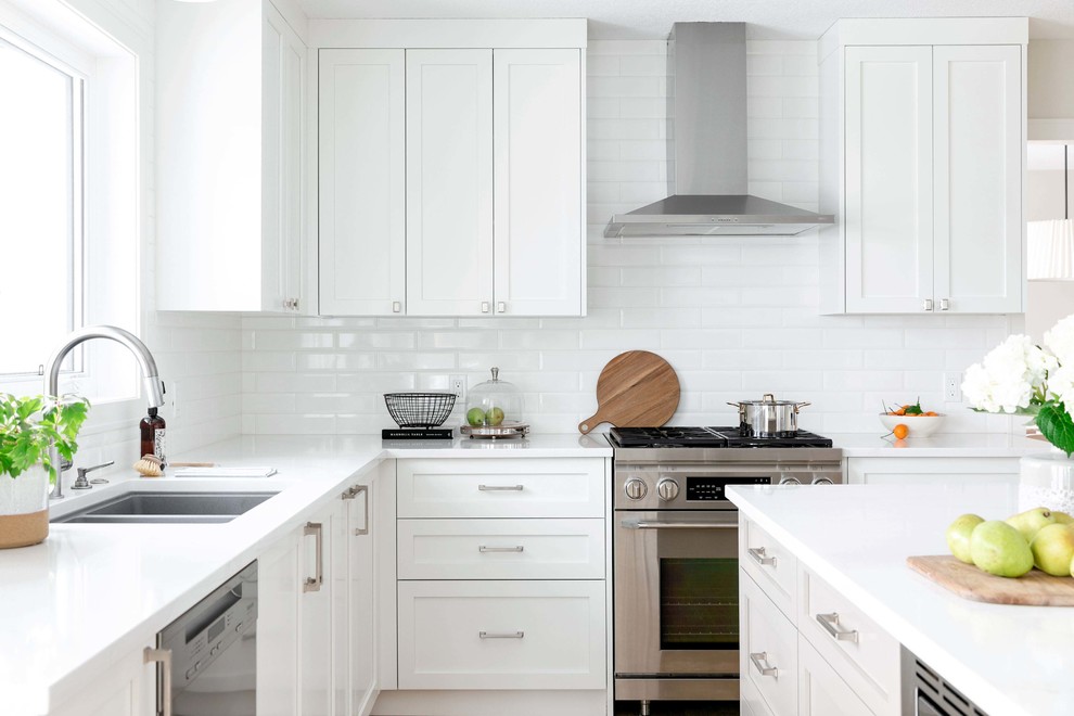 Large transitional u-shaped medium tone wood floor and brown floor eat-in kitchen photo in Calgary with an undermount sink, shaker cabinets, white cabinets, quartzite countertops, white backsplash, subway tile backsplash, stainless steel appliances, an island and white countertops