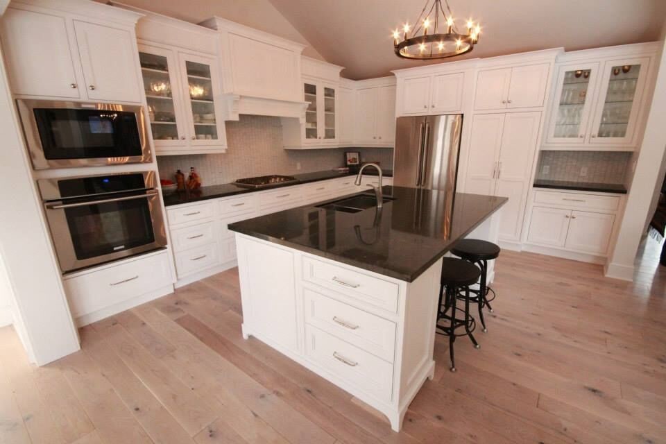 Inspiration for a large transitional l-shaped kitchen in Toronto with a double-bowl sink, recessed-panel cabinets, white cabinets, granite benchtops, grey splashback, ceramic splashback, stainless steel appliances, light hardwood floors, with island and blue floor.