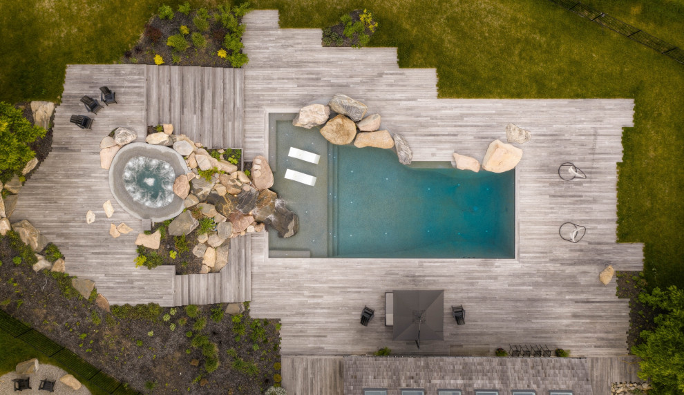 Diseño de piscina tradicional renovada grande rectangular en patio trasero con paisajismo de piscina y entablado
