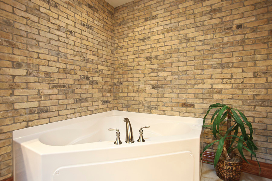 Example of a large mountain style master beige tile and ceramic tile ceramic tile corner bathtub design in Milwaukee with a console sink, shaker cabinets, medium tone wood cabinets, granite countertops, a two-piece toilet and yellow walls