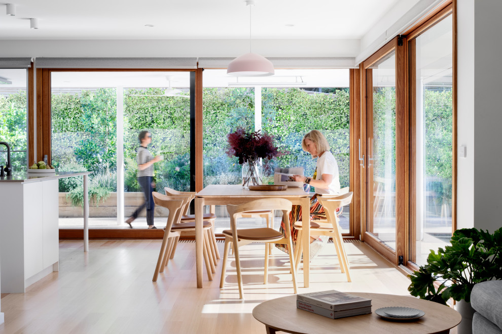 Photo of a contemporary open plan dining in Melbourne with light hardwood floors and no fireplace.
