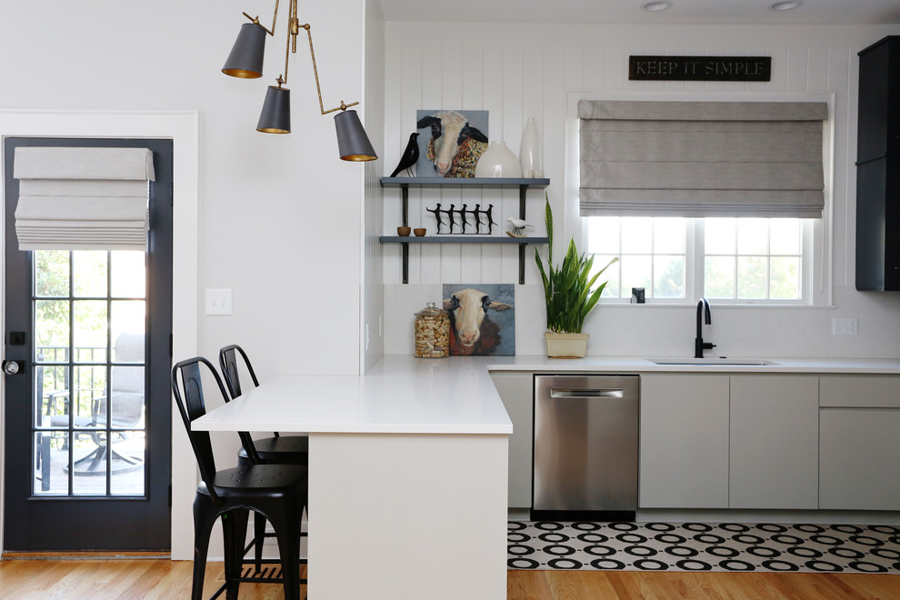 This is an example of a scandinavian eat-in kitchen in Raleigh with an undermount sink, white splashback, stainless steel appliances and a peninsula.
