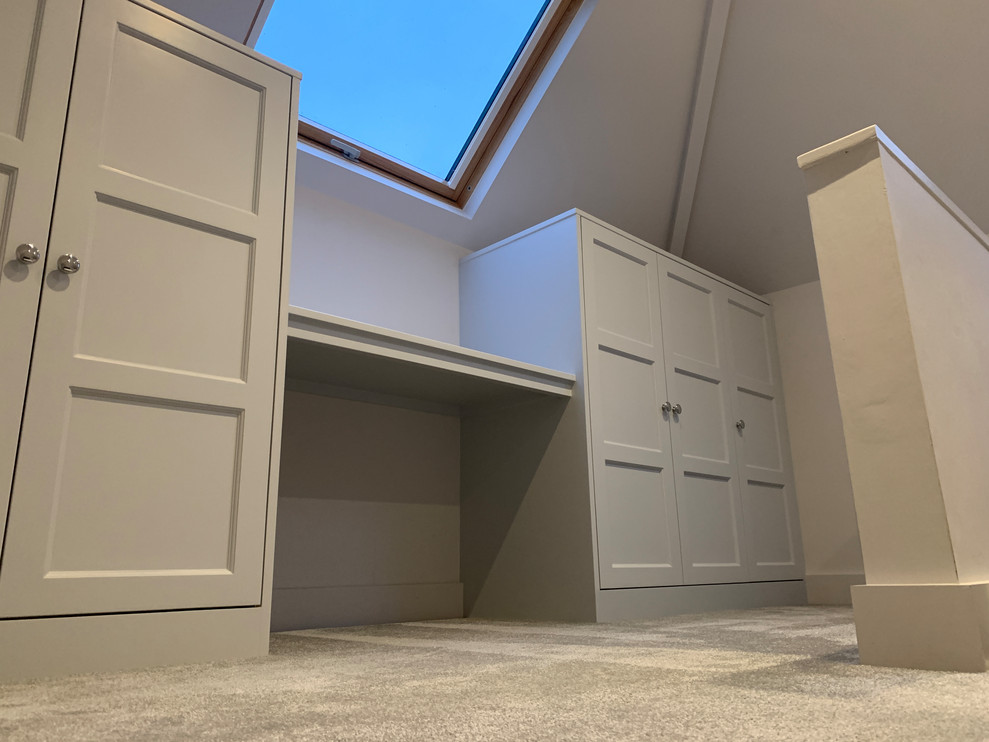 This is an example of a mid-sized beach style gender-neutral dressing room in Dorset with shaker cabinets, grey cabinets, carpet and grey floor.