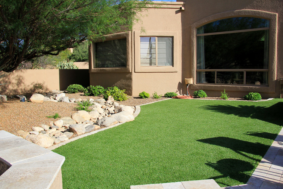 Large mediterranean backyard full sun xeriscape in Phoenix with a retaining wall and gravel for summer.