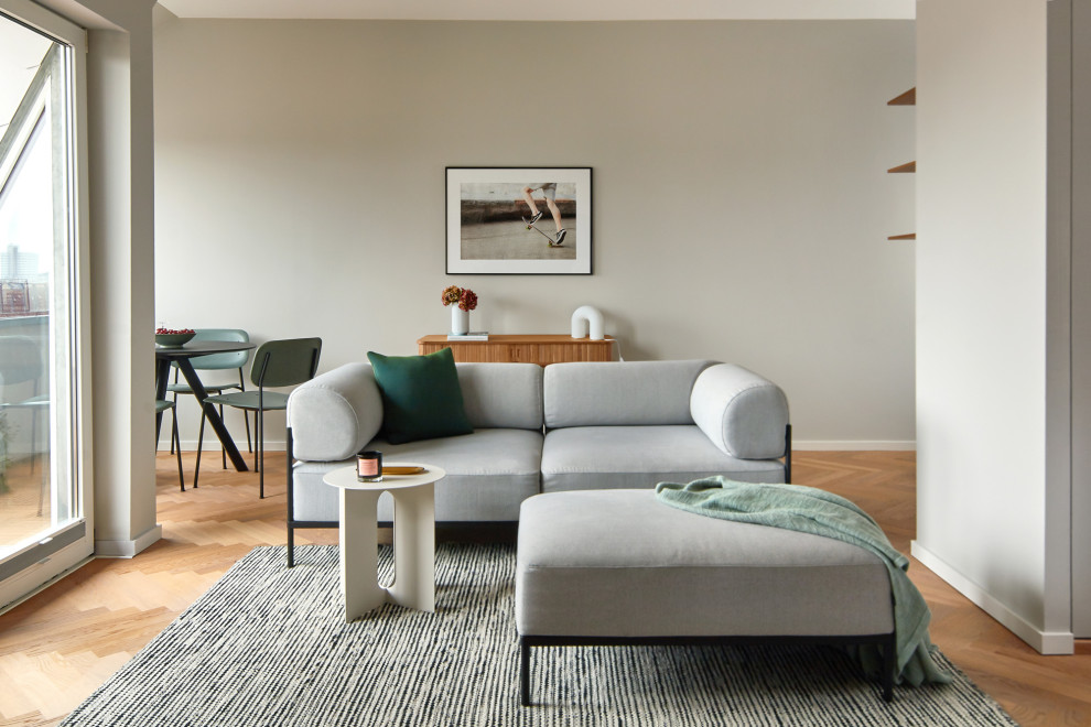 Offenes Modernes Wohnzimmer mit grauer Wandfarbe, braunem Holzboden und braunem Boden in Berlin
