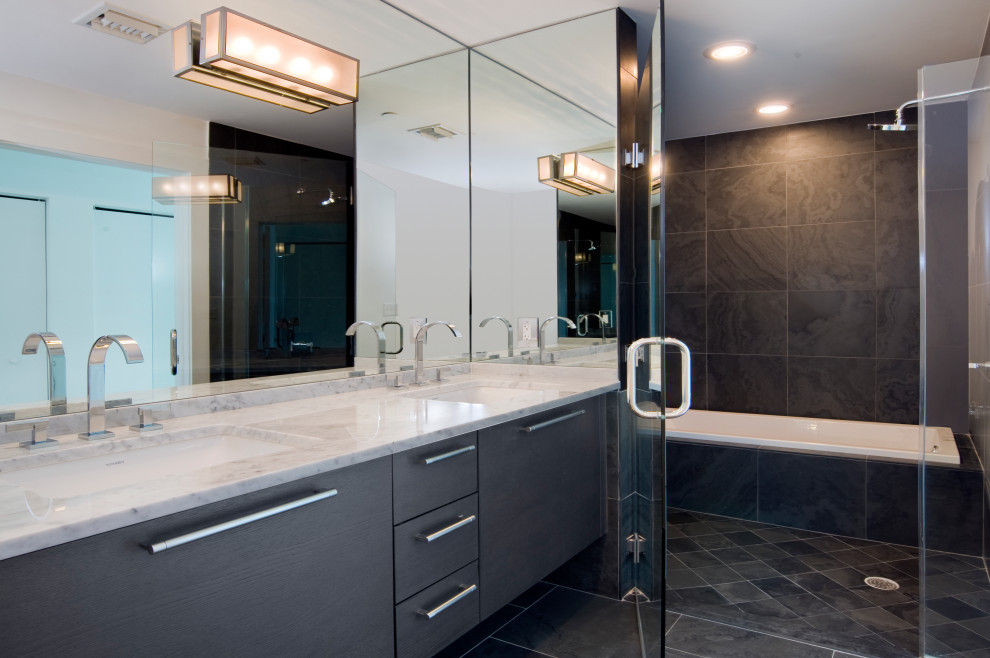 Inspiration for a mid-sized modern master bathroom in Miami with flat-panel cabinets, dark wood cabinets, a drop-in tub, a shower/bathtub combo, a one-piece toilet, gray tile, slate, grey walls, slate floors, a drop-in sink, marble benchtops, grey floor, a hinged shower door, white benchtops, a double vanity and a built-in vanity.