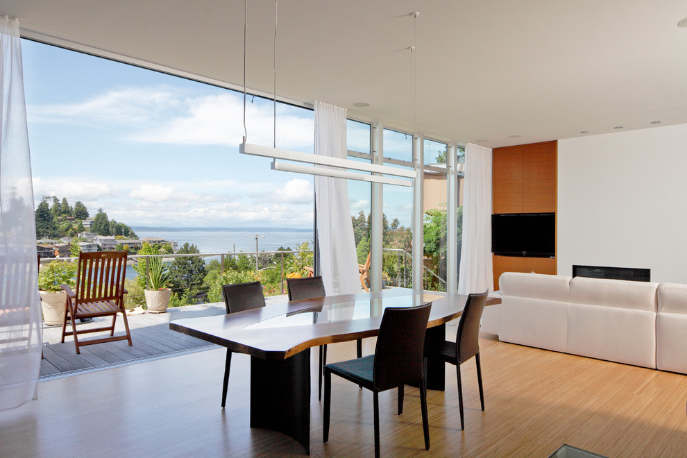 This is an example of a modern dining room in Seattle with white walls, light hardwood floors and a standard fireplace.