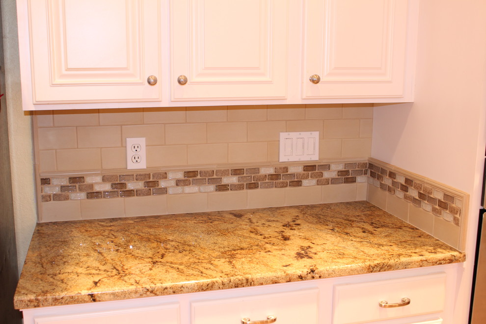 This is an example of a traditional kitchen in Seattle with raised-panel cabinets, white cabinets, beige splashback and glass tile splashback.