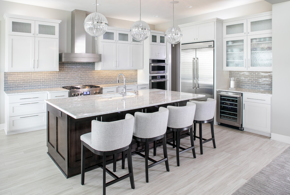 Transitional kitchen photo with shaker cabinets, white cabinets, gray backsplash, stainless steel appliances and an island