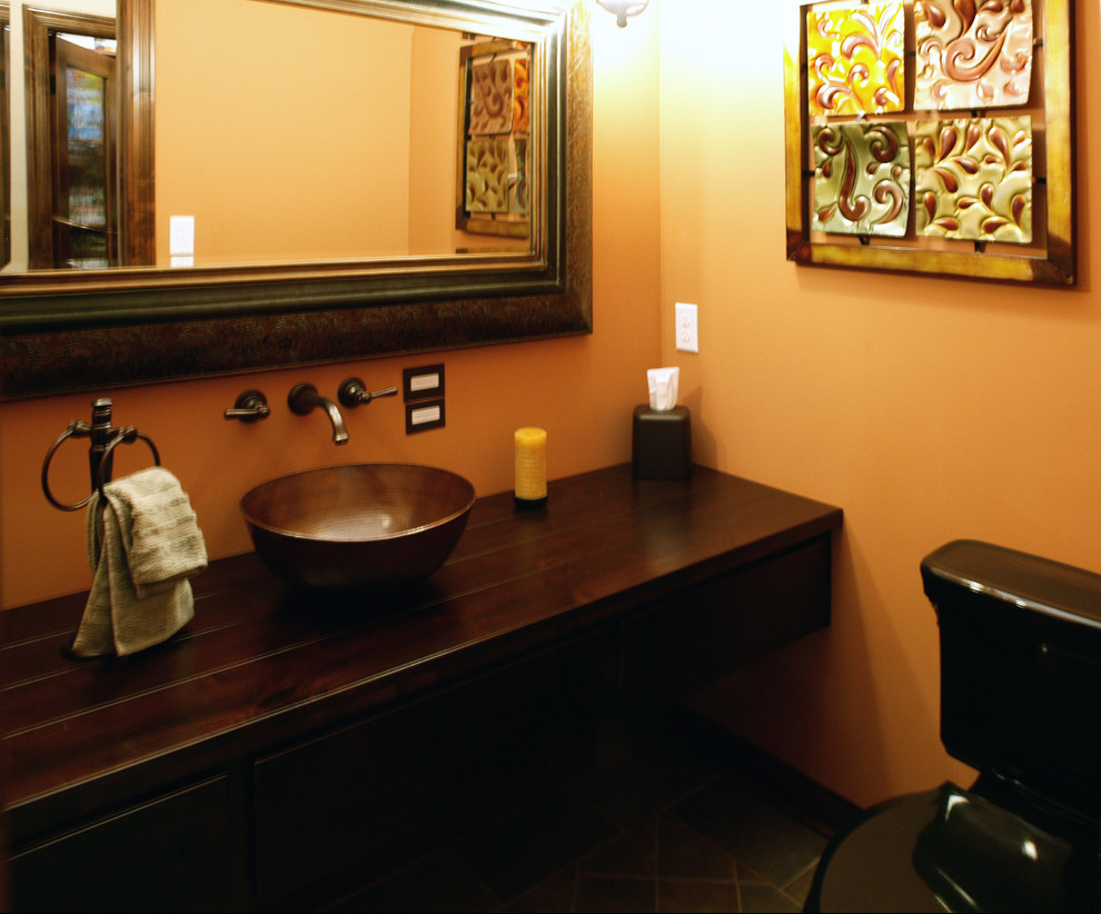 This is an example of a mid-sized traditional bathroom in Minneapolis with furniture-like cabinets, dark wood cabinets, a two-piece toilet, green tile, stone tile, beige walls, slate floors, a vessel sink and wood benchtops.