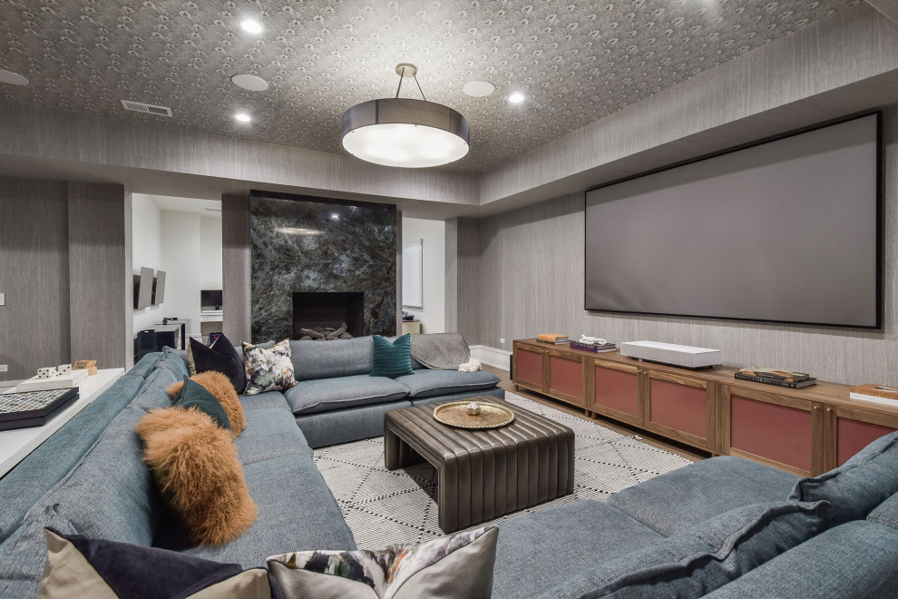 Large eclectic underground light wood floor, wallpaper ceiling and wallpaper basement photo in Chicago with a home theater, gray walls, a standard fireplace and a stone fireplace
