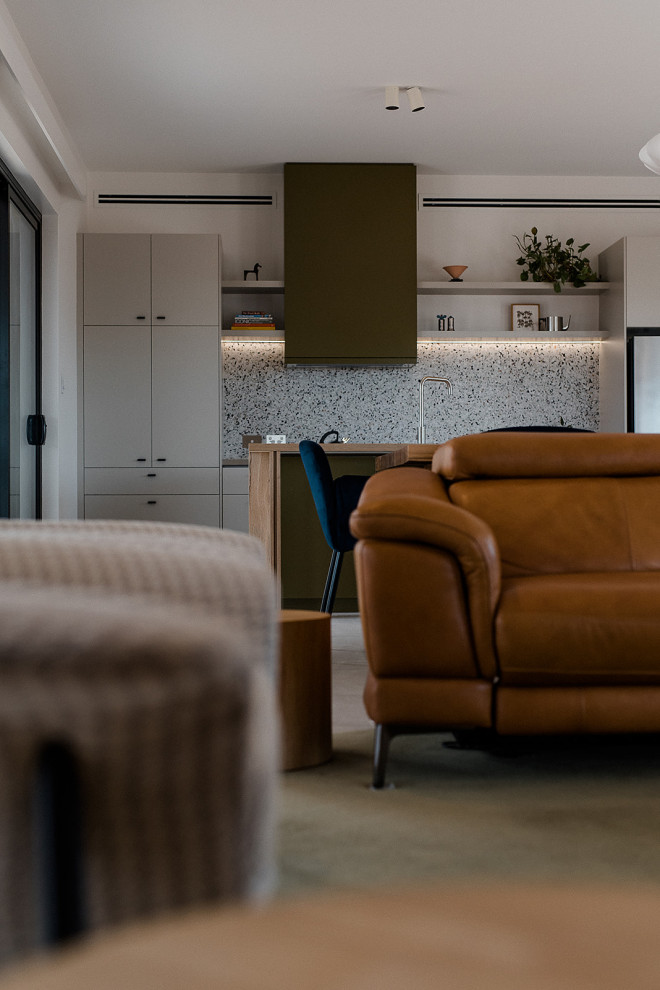 Mid-sized contemporary galley open plan kitchen in Other with a double-bowl sink, flat-panel cabinets, green cabinets, wood benchtops, multi-coloured splashback, stone tile splashback, black appliances, porcelain floors, with island, beige floor and brown benchtop.