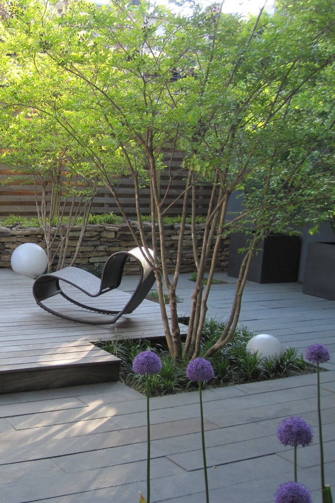 Small modern backyard partial sun garden in New York with natural stone pavers.