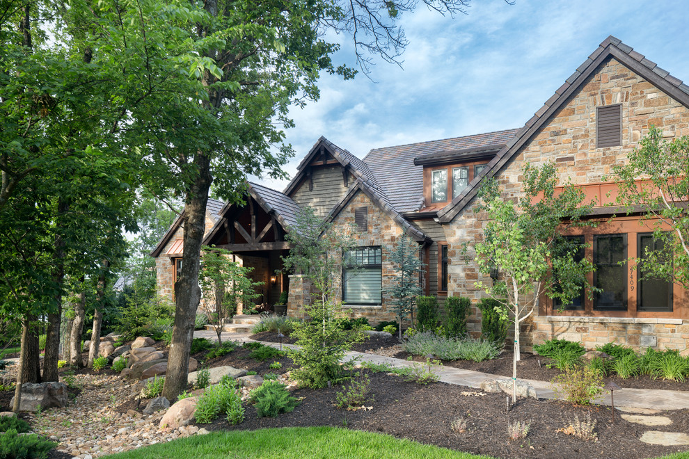 Expansive country two-storey green exterior in Kansas City with stone veneer and a gable roof.