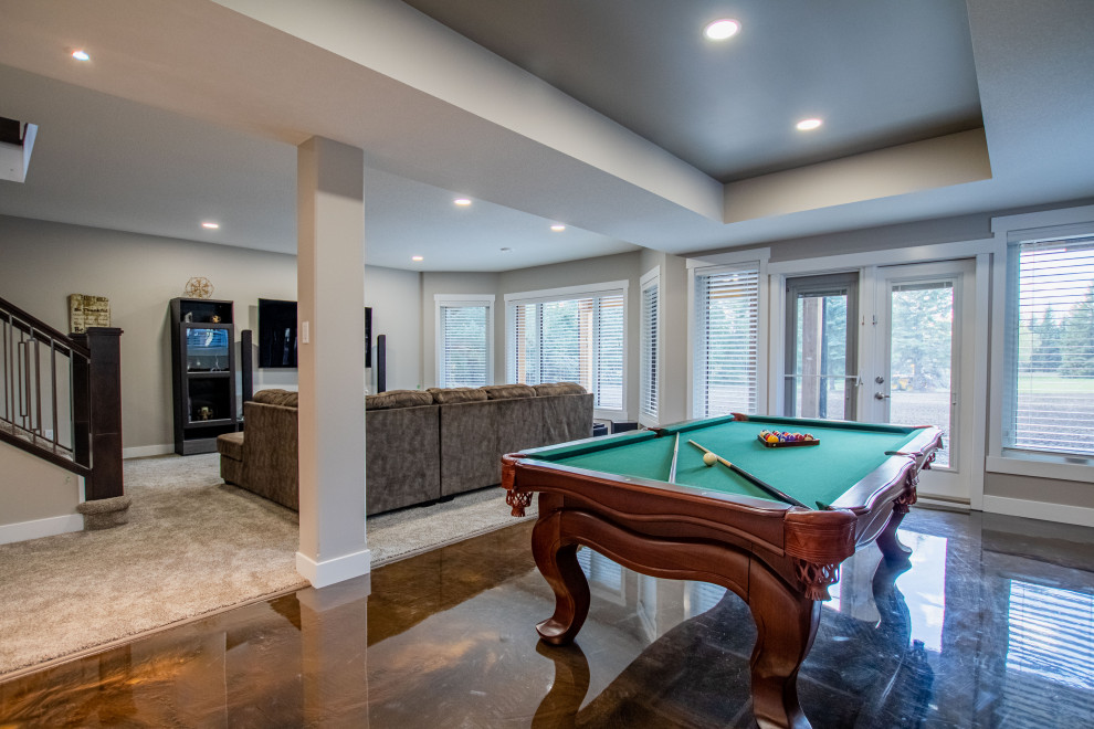 This is an example of a large contemporary walk-out basement in Edmonton with a game room, beige walls, concrete flooring, brown floors and a coffered ceiling.