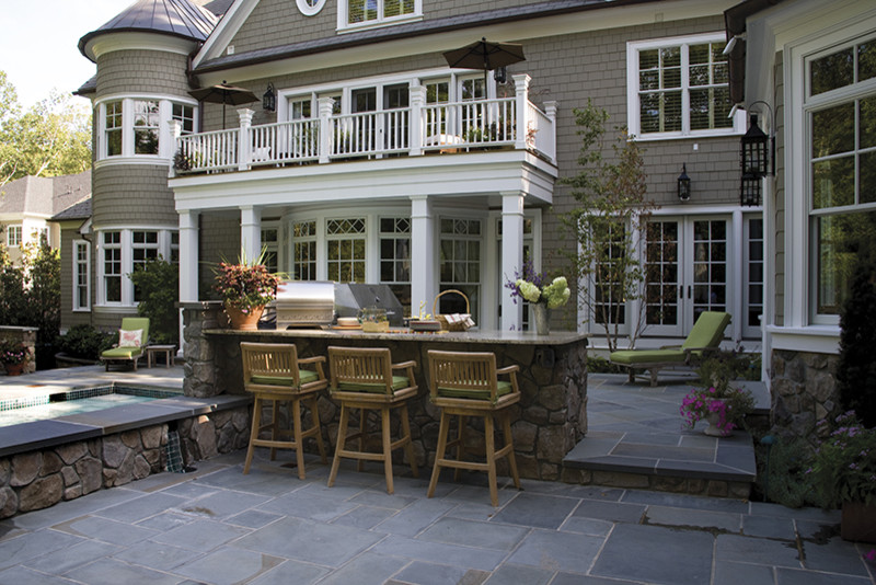 Large backyard patio in Orange County with an outdoor kitchen, natural stone pavers and no cover.