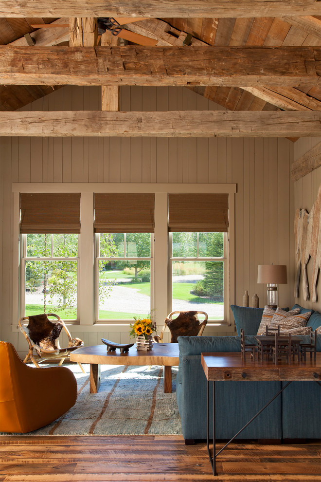 Diseño de salón abierto rústico de tamaño medio con paredes beige, suelo de madera en tonos medios, vigas vistas y machihembrado