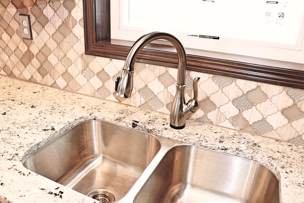 Small transitional u-shaped laminate floor and gray floor eat-in kitchen photo in Cedar Rapids with an undermount sink, recessed-panel cabinets, dark wood cabinets, granite countertops, gray backsplash, mosaic tile backsplash, stainless steel appliances, an island and white countertops