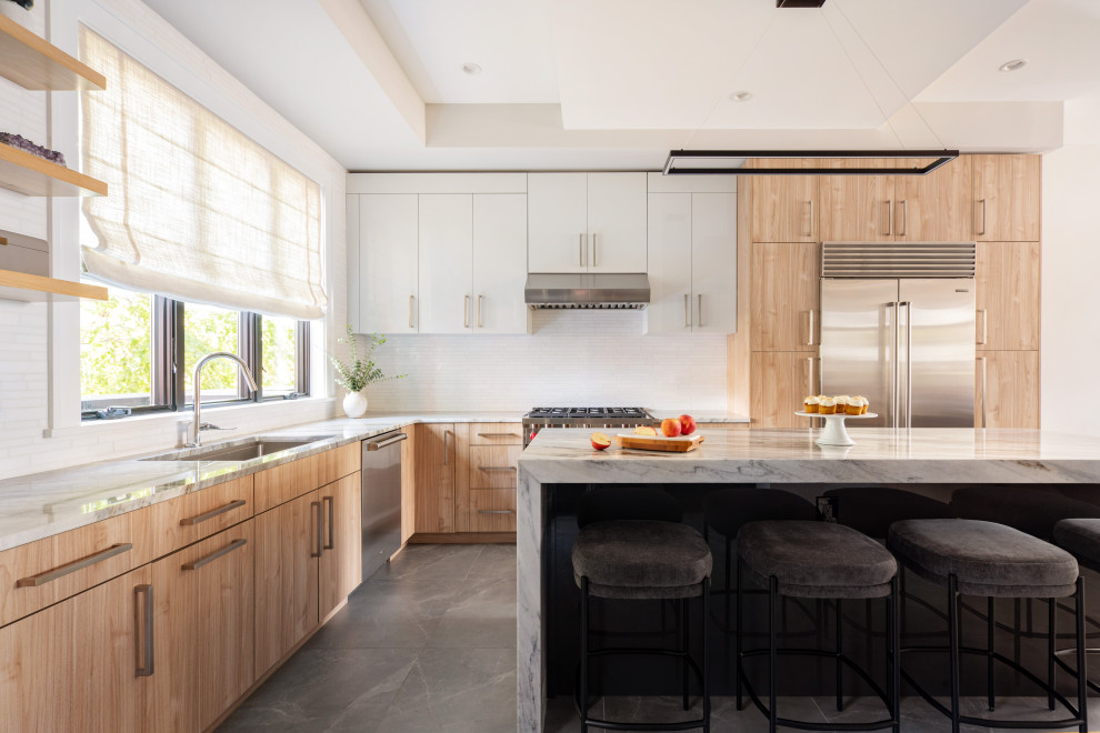 Large classic l-shaped kitchen in Philadelphia with a submerged sink, flat-panel cabinets, light wood cabinets, marble worktops, white splashback, metro tiled splashback, stainless steel appliances, porcelain flooring, an island, grey floors and multicoloured worktops.