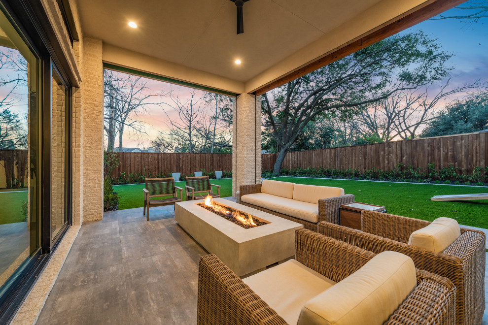 Photo of a large modern backyard patio in Dallas with a fire feature, concrete pavers and a roof extension.