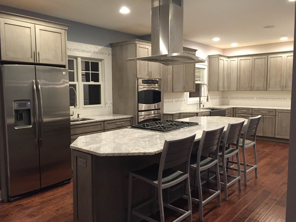 Eat-in kitchen - large transitional l-shaped medium tone wood floor eat-in kitchen idea in Grand Rapids with a farmhouse sink, shaker cabinets, gray cabinets, quartz countertops, white backsplash, porcelain backsplash, stainless steel appliances and an island