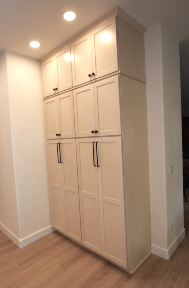 Inspiration for a large transitional l-shaped vinyl floor and beige floor kitchen remodel with an undermount sink, shaker cabinets, light wood cabinets, solid surface countertops, white backsplash, porcelain backsplash, stainless steel appliances, an island and white countertops
