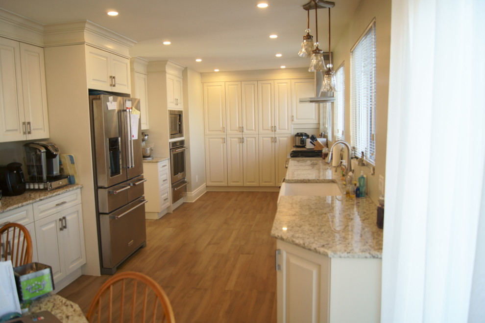 Mid-sized transitional galley medium tone wood floor open concept kitchen photo in Ottawa with a farmhouse sink, raised-panel cabinets, white cabinets, granite countertops and stainless steel appliances