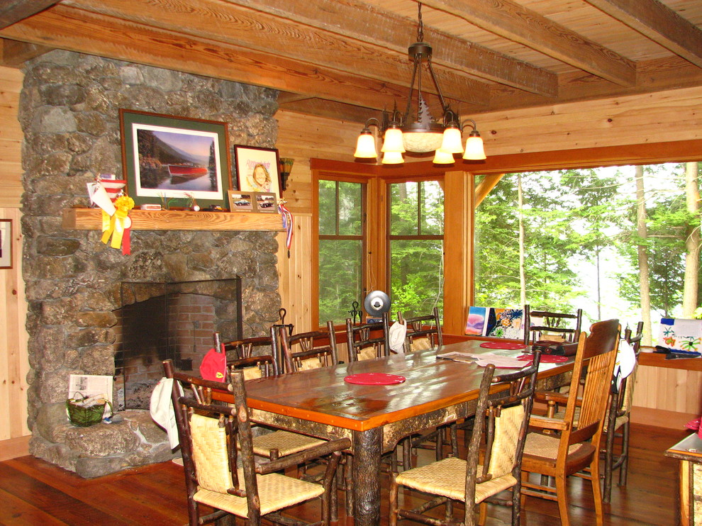 Mid-sized mountain style medium tone wood floor enclosed dining room photo with a standard fireplace and a stone fireplace