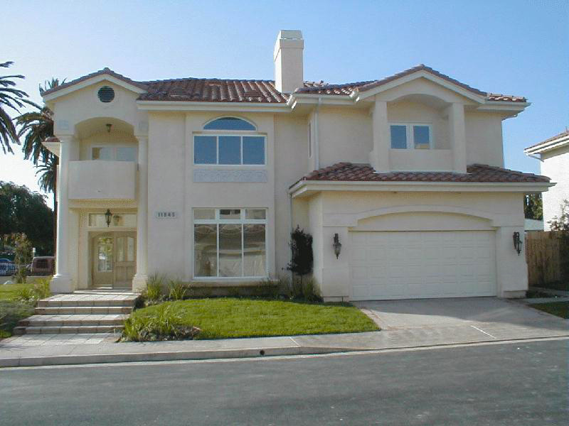 Large traditional two-storey stucco beige house exterior in Los Angeles with a hip roof and a tile roof.