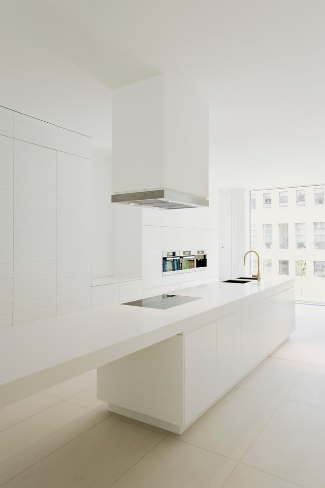 Photo of an expansive modern galley open plan kitchen in Berlin with with island, an undermount sink, flat-panel cabinets, white cabinets, white splashback, black appliances and beige floor.
