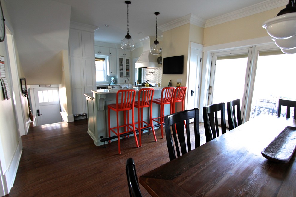 Example of a transitional medium tone wood floor eat-in kitchen design in Omaha with a farmhouse sink, shaker cabinets, white cabinets, quartzite countertops, white backsplash, ceramic backsplash, stainless steel appliances and a peninsula