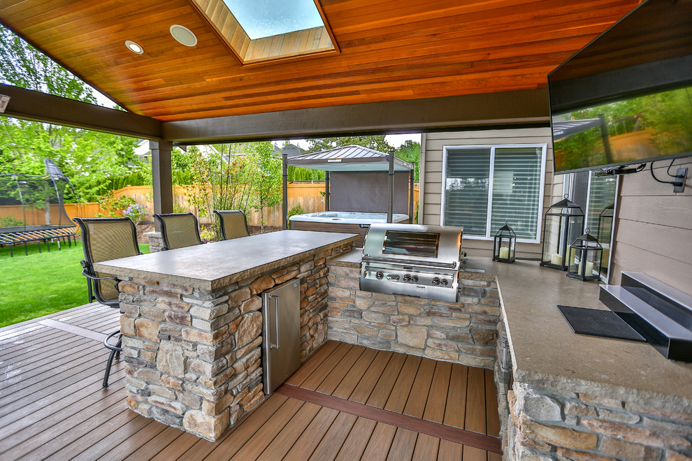 Large traditional backyard deck in Seattle with an outdoor kitchen and a roof extension.