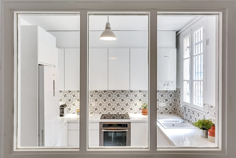 Inspiration for a mid-sized contemporary l-shaped eat-in kitchen in Montpellier with an undermount sink, white cabinets, laminate benchtops, grey splashback, cement tile splashback, porcelain floors, with island, grey floor, flat-panel cabinets, stainless steel appliances and multi-coloured benchtop.