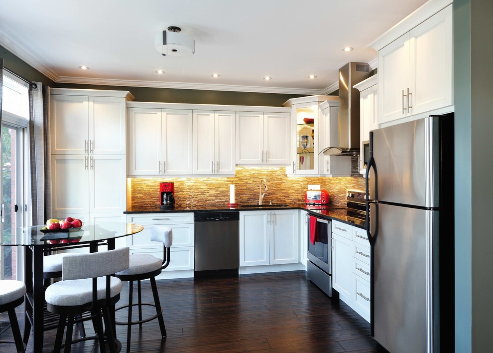 Mid-sized transitional l-shaped dark wood floor eat-in kitchen photo in Ottawa with a single-bowl sink, shaker cabinets, white cabinets, granite countertops, brown backsplash, glass sheet backsplash, stainless steel appliances and no island