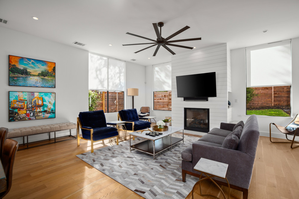 Mid-sized contemporary open concept family room in Austin with white walls, light hardwood floors, a standard fireplace and a wall-mounted tv.