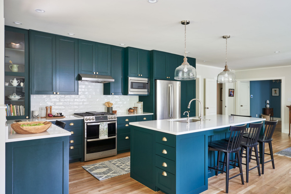 Photo of a medium sized traditional open plan kitchen in Austin with a submerged sink, shaker cabinets, turquoise cabinets, white splashback, stainless steel appliances, medium hardwood flooring, an island and white worktops.