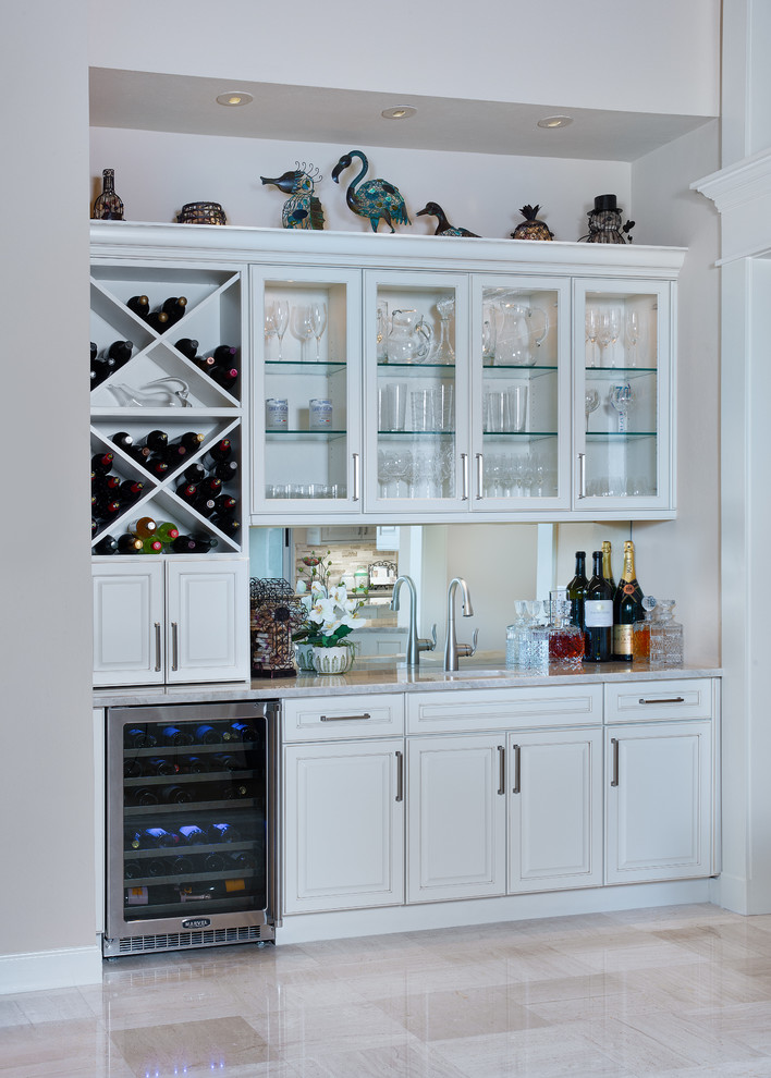 Design ideas for a mid-sized transitional single-wall wet bar in Miami with an undermount sink, raised-panel cabinets, white cabinets, quartzite benchtops, mirror splashback, limestone floors, beige floor and white benchtop.